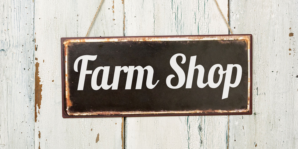 Rustic farm shop sign against a white wooden door 